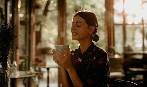 L'immagine mostra una ragazza mentre sorseggia del caffè in un bar